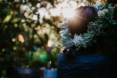 Rear view of woman wearing wreath standing outdoors