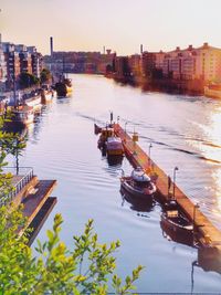 Boats moored on river in city against clear sky