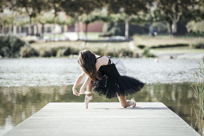 Woman ballet dancing on pier over lake