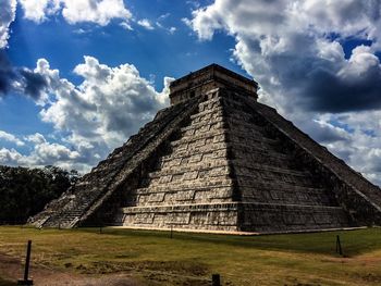 Low angle view of kukulkan pyramid against cloudy sky