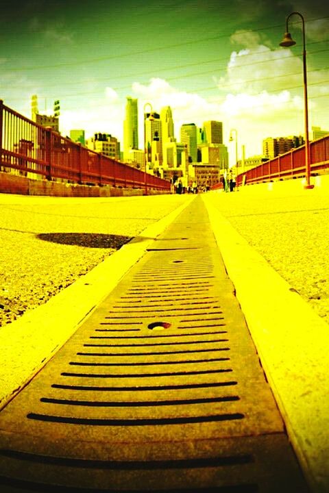 architecture, built structure, building exterior, the way forward, sky, railing, city, building, diminishing perspective, sunlight, empty, incidental people, outdoors, cloud - sky, day, shadow, street, residential structure, yellow, road