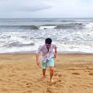 Man walking on beach against sky