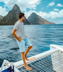 Man standing in sea against mountains