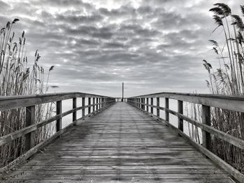 Wooden footbridge over footpath against sky