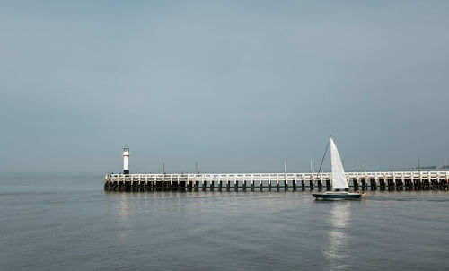 Lighthouse by sea against clear sky