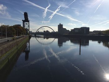 Bridge over river by buildings against sky