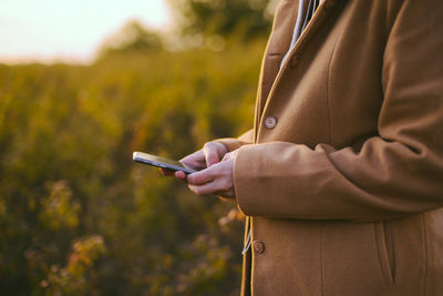 Midsection of woman using phone while standing outdoors