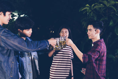 Friends toasting beer glasses outdoors at night