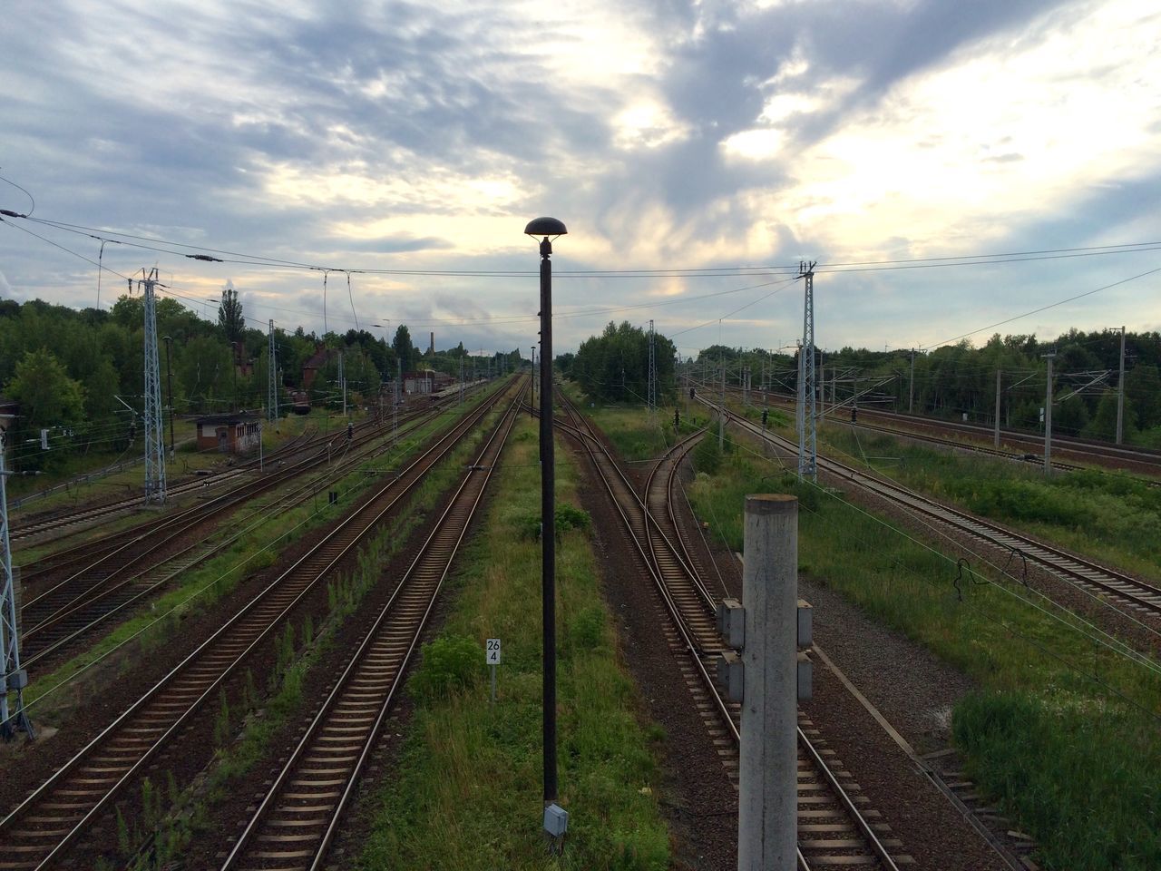 railroad track, rail transportation, sky, the way forward, diminishing perspective, vanishing point, transportation, field, cloud - sky, landscape, growth, agriculture, power line, grass, rural scene, green color, nature, connection, electricity pylon, railway track