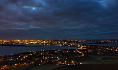 Illuminated cityscape against cloudy sky