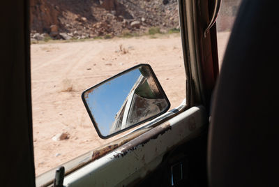 Side-view car mirror with reflection during sunny day