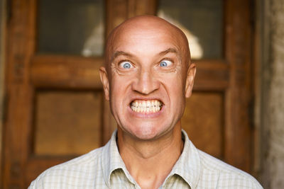 Portrait of an emotional bald guy with blue eyes. dressed in light shirt. shows