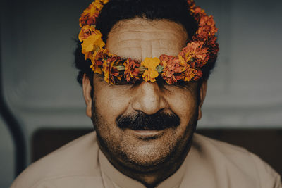 Close-up of man wearing floral garland on head