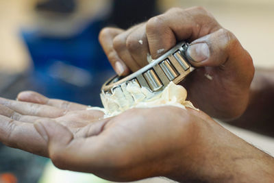 Cropped hands of mechanic holding tool and grease