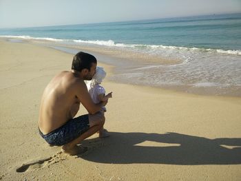 Full length of shirtless man with daughter at beach