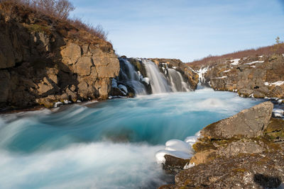 Scenic view of waterfall against sky