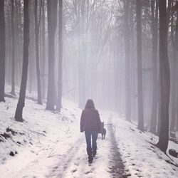 Rear view of woman in snow covered forest