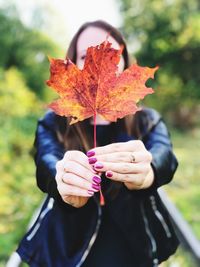 Person holding maple leaf during autumn