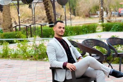 Full length portrait of confident businessman sitting on chair at patio