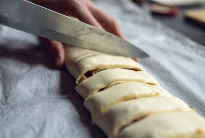 Female hands cut the rolled puff pastry into equal pieces. 