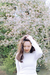 Young woman standing against plants