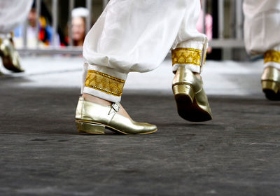 Low section of woman wearing gold colored shoes