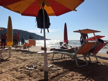 Lounge chairs and parasols on beach against sky