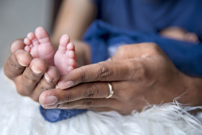 Close-up of mother holding baby while sleeping on bed at home