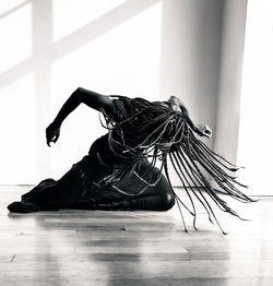 Full length of young woman sitting on floor while dancing during performance at stage