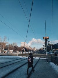 Rear view of man on street against sky in city