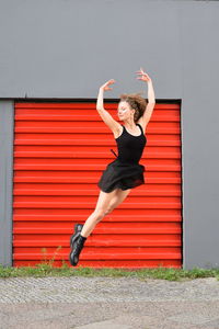 Full length of woman jumping against wall