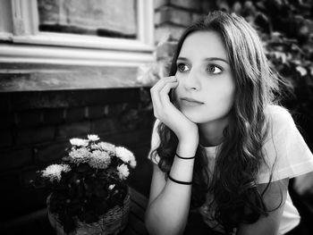 Portrait of beautiful woman sitting by potted plant