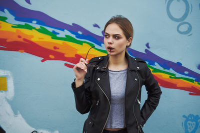 Young woman standing against graffiti wall