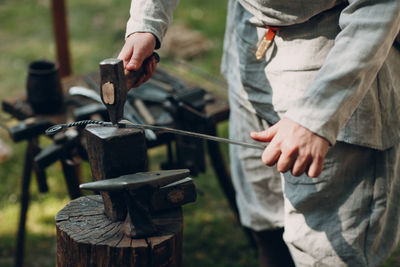 Midsection of blacksmith hammering metal