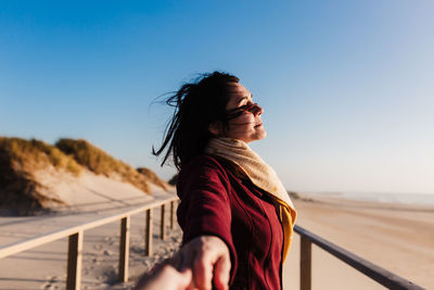 Young woman with eyes closed relaxing at beach at sunset. holidays and relaxation concept