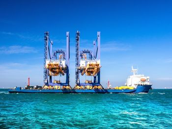 Cranes in sea against blue sky