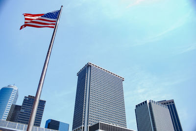 Low angle view of flags against buildings in city against sky