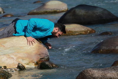 Man lying on rock at river