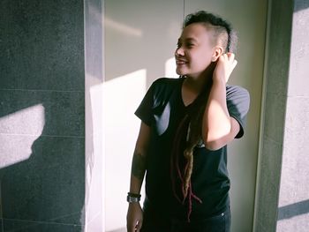 Smiling young woman standing against wall