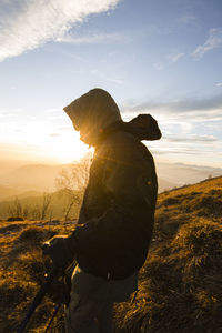 Side view of man standing on mountain against sky