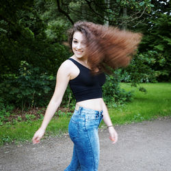 Portrait of smiling young woman with tousled hair standing on road