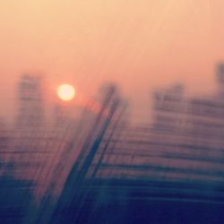 Defocused image of city against sky during sunset