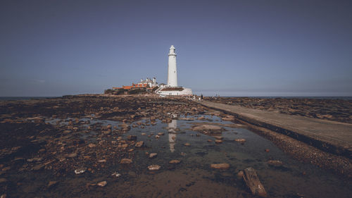 Lighthouse on beach against clear sky