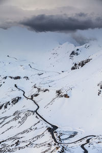 Flock of birds on snow covered mountain against sky