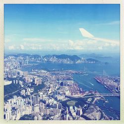 Aerial view of city by sea against blue sky