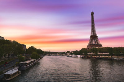 River in city against sky during sunset