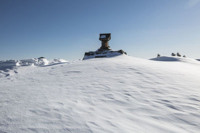 Snow covered land against clear sky