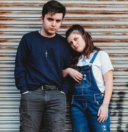 Portrait of young couple standing against wall