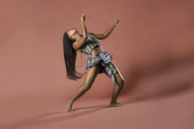 Young woman dancing against brown background