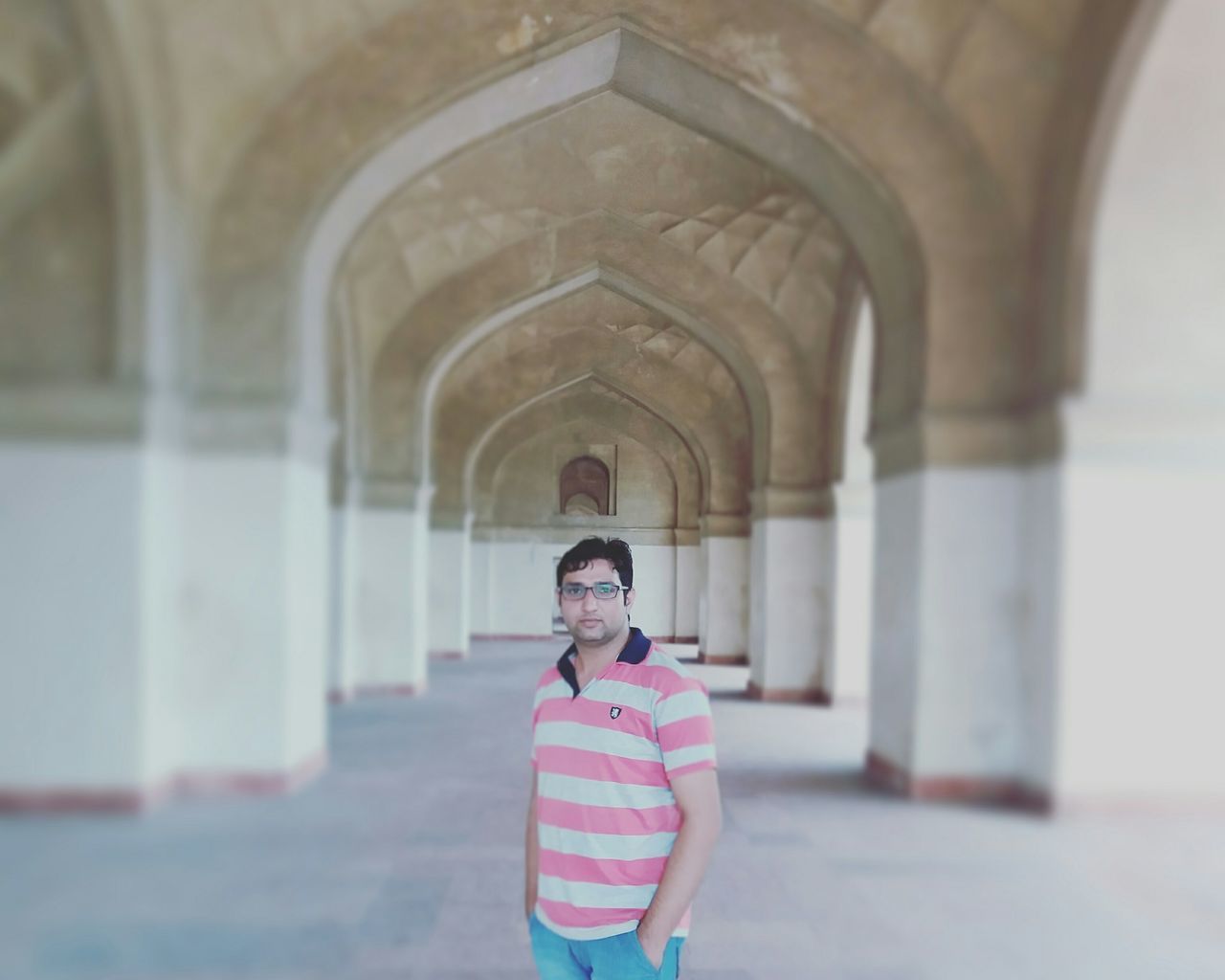 PORTRAIT OF MATURE MAN STANDING IN CORRIDOR